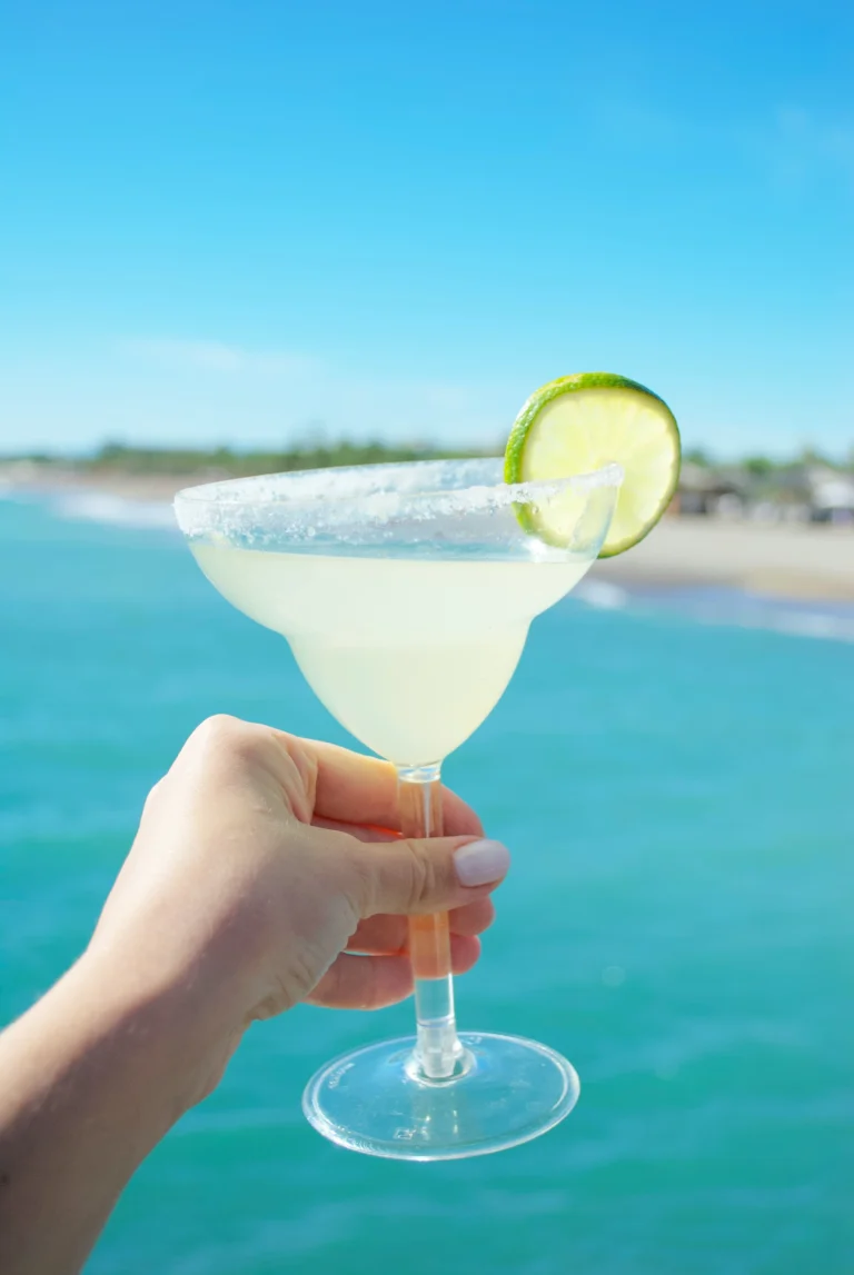tropical drink held in front of caribbean ocean